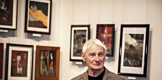 Janusz Dziduszko na tle swych prac wystawianych ostatnio w muzeum w Gorlicach